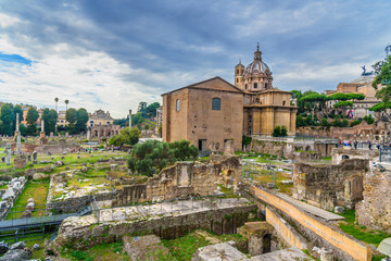 Fototapeta na wymiar Ruins of Roman Forum. Curia Julia, Roman columns and church of Santi Luca e Martina. Rome. Italy
