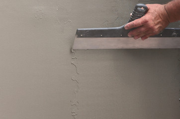 Hands of an old manual worker with wall plastering tools renovating house. Plasterer renovating...
