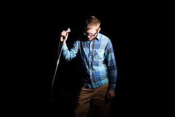 Musician singing to the microphone on a concert in stage backlights