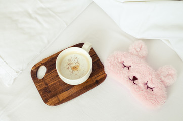 Cup of coffee with cute pink sleep mask