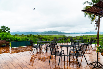 Varanda with a view of mountainous range and the lake of the reservoir on rainy day. There is a big bird flying in the cloudy sky background and copy space.