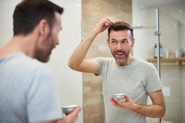 Mature man applying hair gel in the bathroom