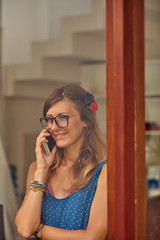 Young woman using smart phone indoors. Window reflection from outdoors.