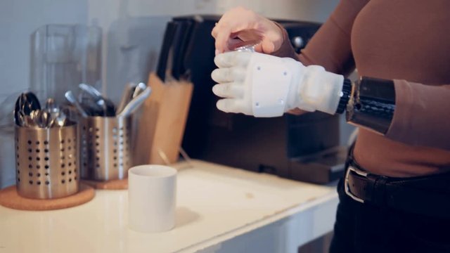 A lady with a bionic hand adds spice into the cup