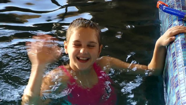 The girl swims in the pool. Splashing water and having fun. In the water, bathe and play. Happy to rest and bathe. Swim in the pool. Lead a healthy lifestyle.