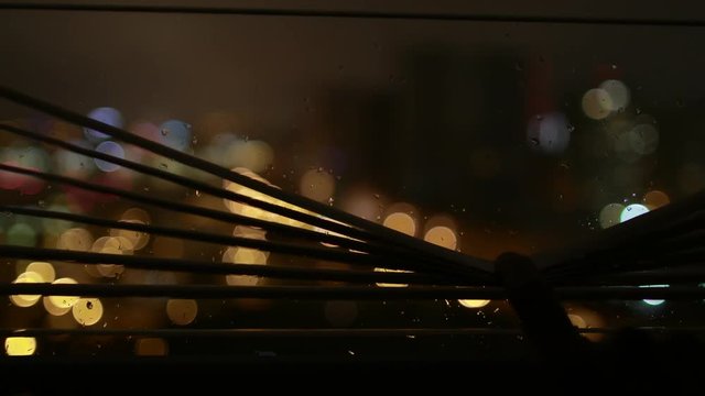 Night city life while raining through jalousie window.