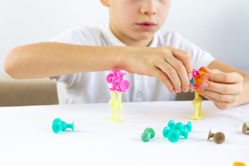 Close-up of child playing board game while sitting at the table at home, suction cup construction sets for child development