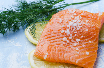 Closeup of piece of salmon,dill,seasalt,slices of lemon on blue table