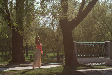 Beautiful and elegant girl in a long red dress stands in the middle of the medieval castle