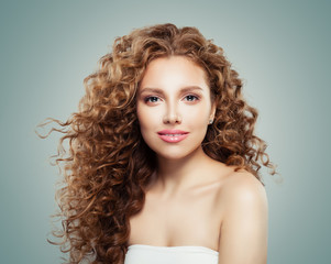 Beautiful smiling woman with healthy curly hair on gray background. Redhead girl