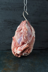 Vertical photo.Concept of meat hook.Huge piece of pork against black wall