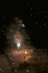Bright colorful multicolored fireworks fountain in the snow at night