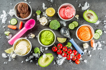 Trendy vegan food, summer healthy dessert concept, colorful diet vegetable ice cream with avocado, cucumber, tomato, beet, carrot, broccoli, cauliflower. Frozen veggie smoothie, black background