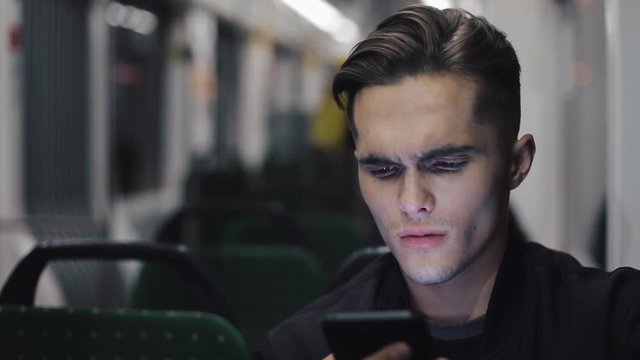 Unhappy young businessman with smartphone reading bad news riding in public transport