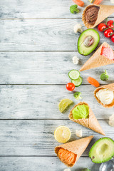Trendy vegan food, summer healthy dessert concept, colorful diet vegetable ice cream with avocado, cucumber, tomato, beet, carrot, broccoli, cauliflower. Frozen veggie smoothie, wooden background