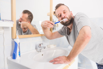 Obraz premium Man brushing his teeth in bathroom