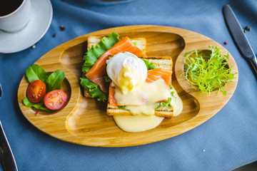 sandwich with salmon and egg on a wooden plate. breakfast