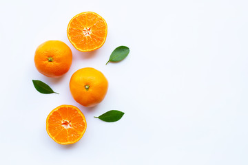 Orange citrus fruit with green leaves on white.