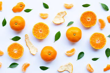 Fresh orange citrus fruit with peel and green leaves on white