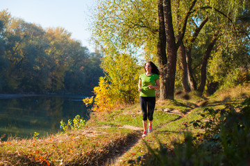 Fototapeta premium Portrait of smiling woman jogging near the pond