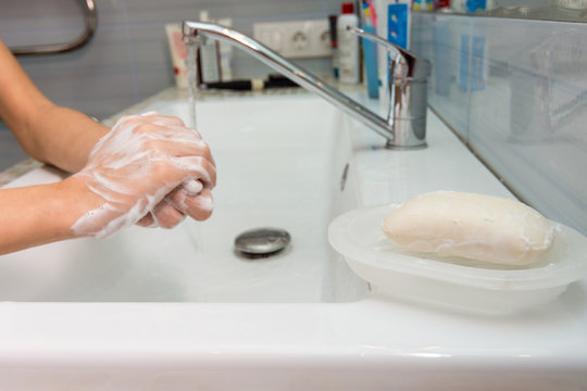 The child carefully washes his hands with soap, in the foreground a bar of soap