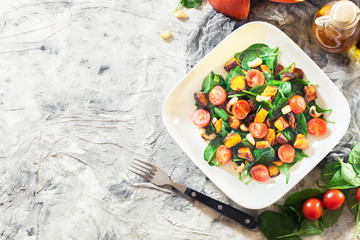 Fototapeta na wymiar Roasted pumpkin salad with spinach, tomatoes and nuts