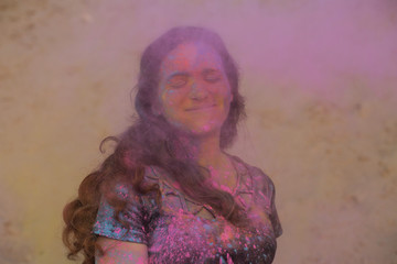 Gorgeous brunette woman enjoying Holi festival at the desert. Woman posing with exploding pink paint
