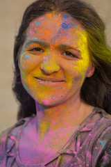 Lovely brunette model with wavy hair covered with colorful dry paint Holi at the desert