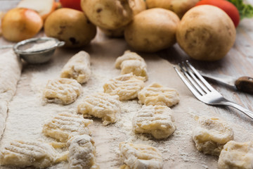 Homemade uncooked potato gnocchi. Raw Italian dumplings on a floured wooden board in a kitchen