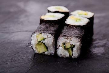 Cucumber sushi roll on black slate board