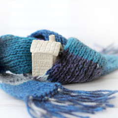 real estate insulation concept. cold house wrapped in a warm scarf