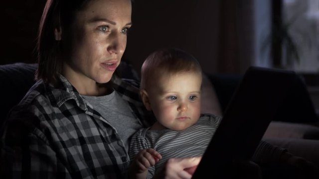 Mother with baby girl using digital tablet at night