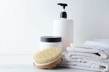 White towels and bottles with shampoo,cream,body brush for spa treatments against white background  at the bath marble shelf