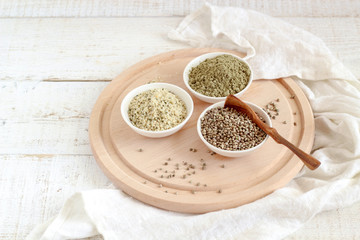 Organic hemp whole seeds, hulled seeds and protein powder in bowls on a white wooden background
