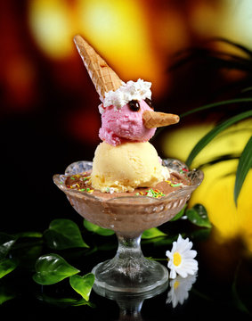 Copa de helado, con una presentaci&oacute;n para ni&ntilde;os. Gustos de chocolate, vainilla y fresa, nata montada y unos trocitos de galleta como sombrero y pico.