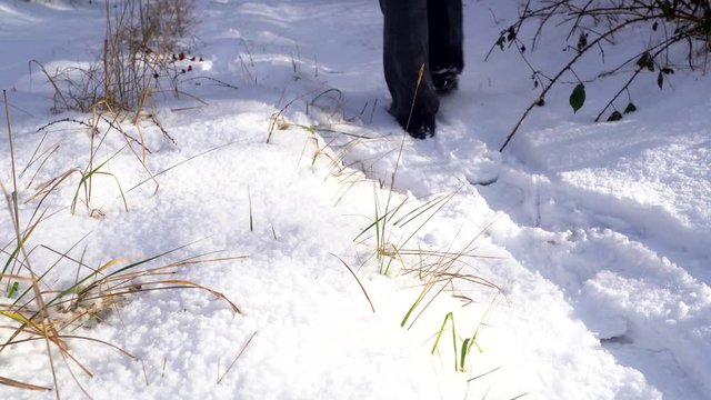 Man walks in the snow. Snow covered trail close-up. Hiking in a sunny cold winter day.