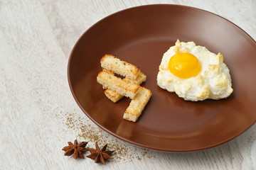 Orsini egg and croutons on a brown plate.