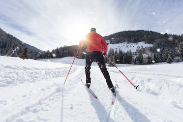 Man cross-country skiing during sunny winter day.