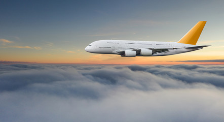 Huge two-storey passengers commercial airplane flying above dramatic clouds, sunset.