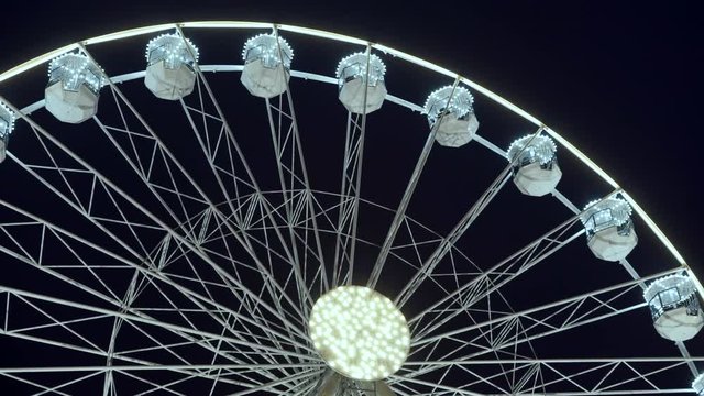 Part of beautifully lighted ferris wheel against a night sky background.
