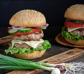 burger with two fried cutlets, cheese and vegetables