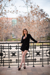 Pretty model woman posing in a park resting on a fence	