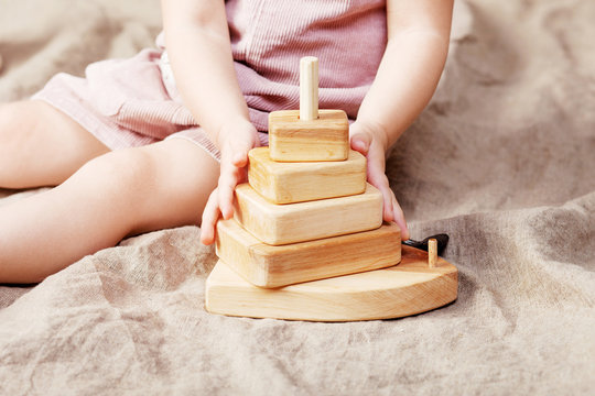 Child girl playing with a wooden toy pyramid. Little cute girl with  natural toys.  Close up picture