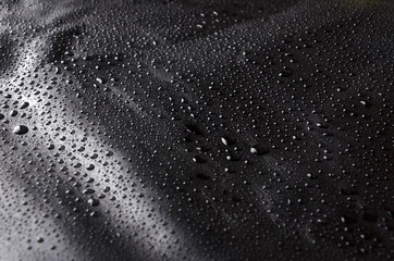 Water drops on black leather, dark natural background