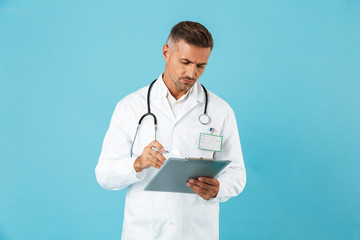 Portrait of caucasian medical doctor with stethoscope holding health card, standing isolated over blue background