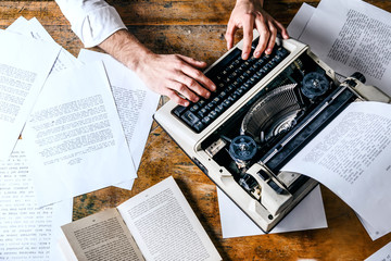 Young man's hands typing on an antique vintage typewriter