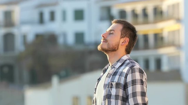 Side view portrait of a relaxed guy breathing fresh air in a town