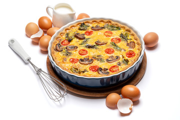 Baked homemade quiche pie in ceramic baking form, eggs and cream