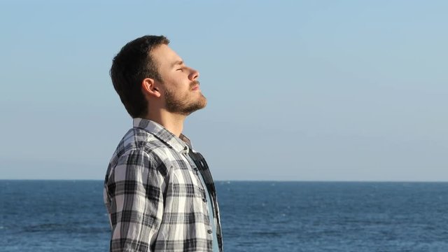 Side view portrait of a happy man relaxing breathing fresh air on the beach