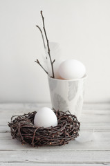 Easter. White eggs on a wooden table with feathers and branches